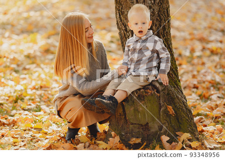 Family in a autumn park. Mother in a brown sweater. Cute little boy in a shirt Family in a autumn park. Mother in a brown sweater. Cute little boy in a shirt 93348956