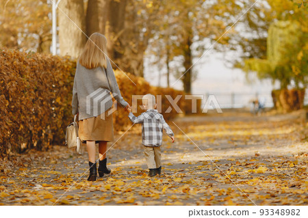 Family in a autumn park. Mother in a brown sweater. Cute little boy in a shirt 93348982