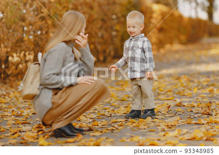 Family in a autumn park. Mother in a brown sweater. Cute little boy in a shirt Family in a autumn park. Mother in a brown sweater. Cute little boy in a shirt 93348985