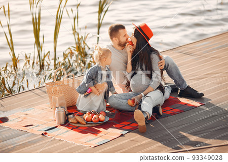 Family in a autumn park. Mother in a red hat. Cute little girl with parent on a picnic 93349028
