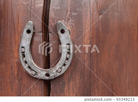 Old horseshoe on wooden wall background. Farm authentic entourage. Good luck, safety. Protect from breaking apart, failure misfortunes. Superstitions, beliefs. Problem solution. Property insurance 93349213