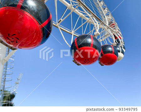 amusement park. Ferris wheel made of white metal. On the wheel there are large cabins for riding red tourists 93349795
