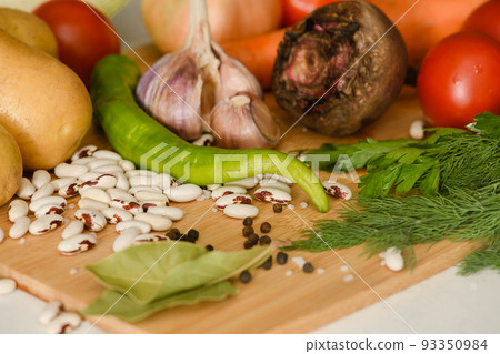 Vegetables and spices on a wooden cutting board in the kitchen. Vegetables and spices on a wooden cutting board in the kitchen. 93350984