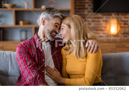 Smiling happy mature caucasian male with beard and female look at each other, couple have fun together 93352062