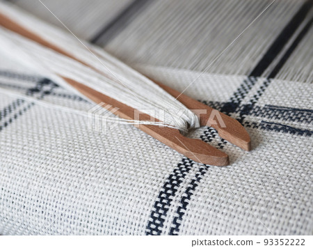Black and white weaving project. Wooden shuttle with thread on the handloom 93352222