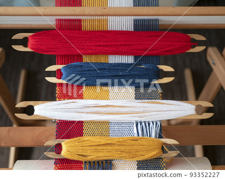 Four shuttles with yarn of different colors on the loom. Weaving shuttles with colored threads on the weaving project 93352227