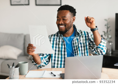 Black Man At Laptop Celebrating Success Holding Paper At Workplace 93352234