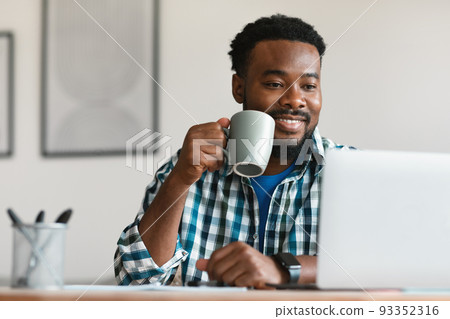 Black Male Having Coffee Using Laptop Working Online In Office 93352316