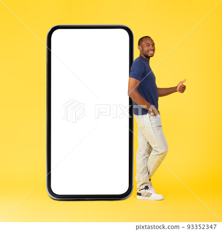 African Guy Leaning On Smartphone Gesturing Thumbs Up, Yellow Background 93352347