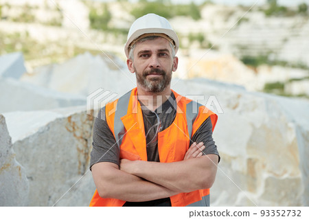 Confident mature foreman in hardhat and workwear crossing arms on chest 93352732