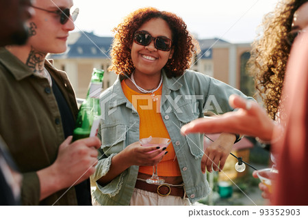 Happy young black woman in sunglasses and casualwear holding cocktail Happy young black woman in sunglasses and casualwear holding cocktail 93352903