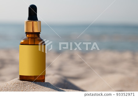 Mock-up for a medicinal or cosmetic product. A bottle with a dropper and gold cap on the sand of the beach, copy space. Mock-up for a medicinal or cosmetic product. A bottle with a dropper and gold cap on the sand of the beach, copy space. 93352971