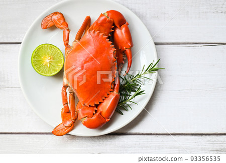 seafood plate with herbs spices rosemary lemon lime, fresh crab on white plate, crab cooking food boiled or steamed crab red in the restaurant 93356535