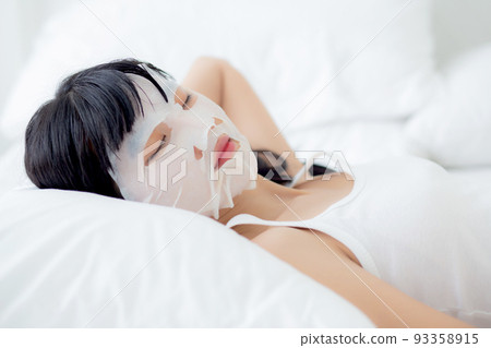 Beautiful young asian woman with sheet facial mask and sleep on bed at bedroom. Beautiful young asian woman with sheet facial mask and sleep on bed at bedroom. 93358915