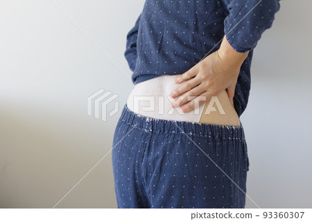 Back view of a woman who puts her hand on her waist with a poultice 93360307