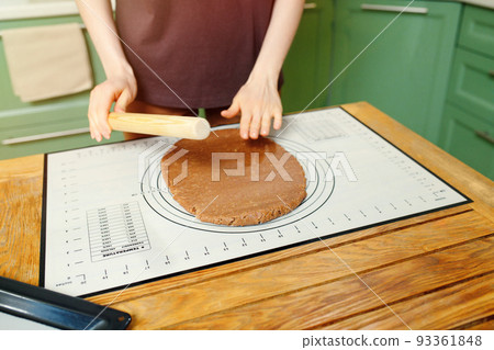 Rolling out shortcrust pastry for home bakery on a silicone baking mat on a wooden table 93361848