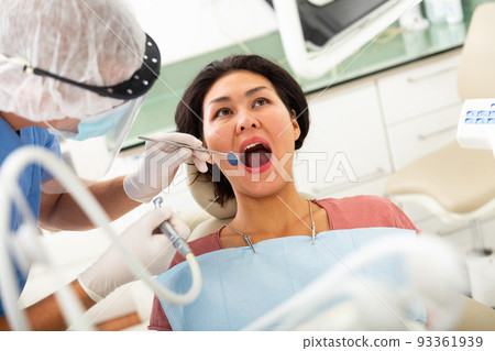 Dentist drilling tooth to asian female patient 93361939