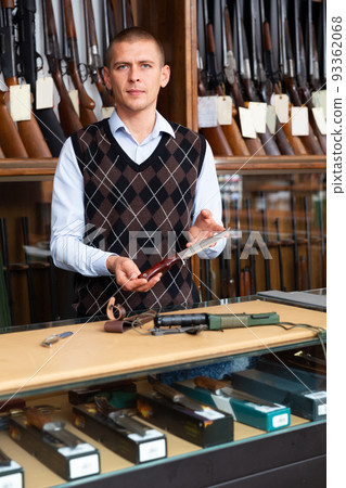 Gunsmith shop assistant demonstrates hunting knife in hands Gunsmith shop assistant demonstrates hunting knife in hands 93362068