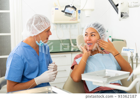 Woman complains of toothache to dentist Woman complains of toothache to dentist 93362187