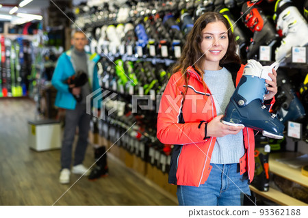 Client female in skiing equipment is choosing boots for skiing Client female in skiing equipment is choosing boots for skiing 93362188
