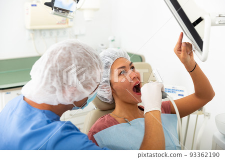 Dentist checks the patient teeth using special instrument and computer Dentist checks the patient teeth using special instrument and computer 93362190