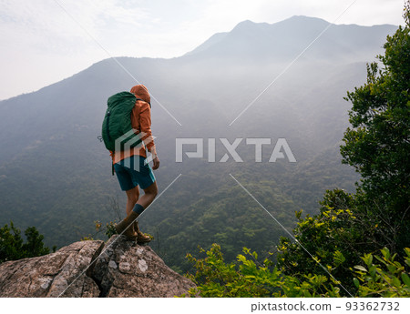 Fearless woman hiker looking at the cliff edge on mountain top Fearless woman hiker looking at the cliff edge on mountain top 93362732