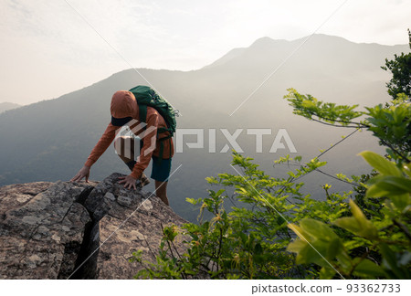 Suceesful woman hiker climbing up at the cliff edge on mountain top Suceesful woman hiker climbing up at the cliff edge on mountain top 93362733