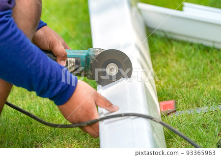 worker cutting pvc trough / spout for rooftop rainwater drain, a part of home improvment photo. 93365963