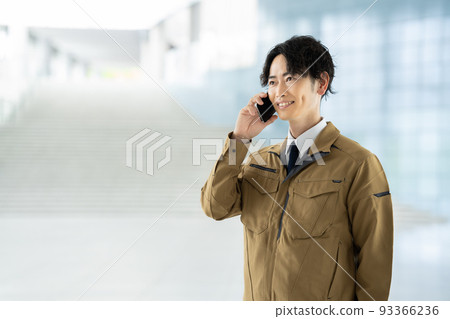 A man in work clothes making a phone call A man in work clothes making a phone call 93366236