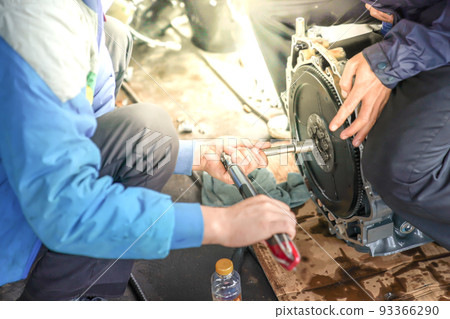 2 mechanic men try to fix and setup boat engine with glowing light. 93366290