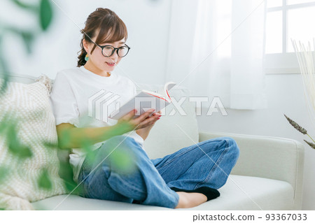 Fashionable Japanese women reading on the sofa at home (books, manga, novels) 93367033