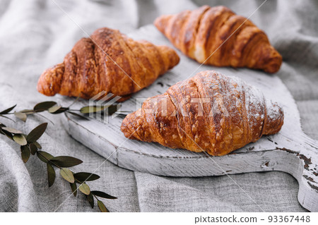 Close up three freshly baked croissants with sugar powder on a wooden desk 93367448