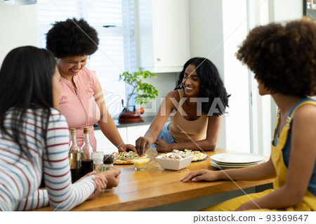 Cheerful biracial young friends making pizza on kitchen island while enjoying weekend at home Cheerful biracial young friends making pizza on kitchen island while enjoying weekend at home 93369647
