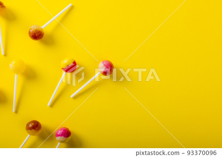 Directly above view of lollipops scattered by copy space over yellow background Directly above view of lollipops scattered by copy space over yellow background 93370096
