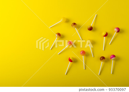 Overhead view of lollipops scattered by copy space against yellow background Overhead view of lollipops scattered by copy space against yellow background 93370097