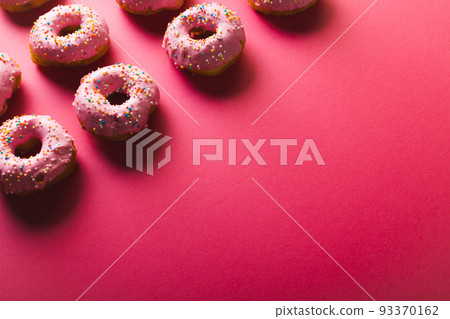 High angle view of copy space by arranged donuts with sprinklers on pink background High angle view of copy space by arranged donuts with sprinklers on pink background 93370162