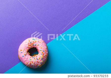 Directly above view of fresh pink donut with sprinklers by copy space against two tone background Directly above view of fresh pink donut with sprinklers by copy space against two tone background 93370233