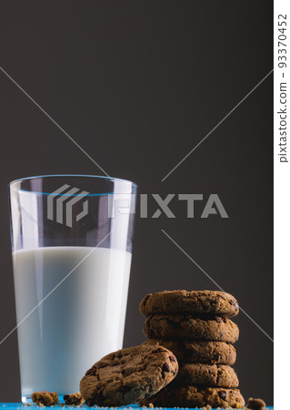 Low angle view of milk glass by stacked cookies against gray background, copy space 93370452