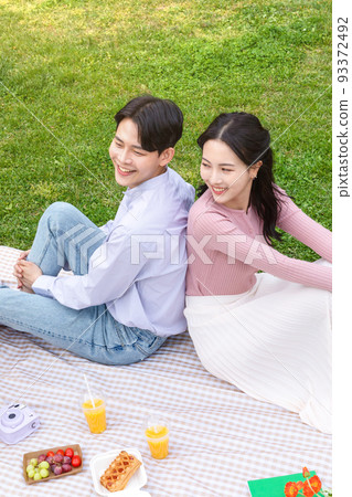 Asian Korean couple enjoying spring picnic_leaning against each other 93372492