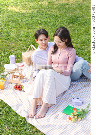 Asian Korean couple enjoying spring picnic_watching tablet pc 93372495