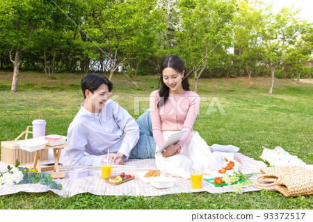 Asian Korean couple enjoying spring picnic_watching tablet pc 93372517