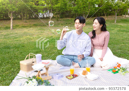 Asian Korean couple enjoying spring picnic_playing with bubbles 93372578
