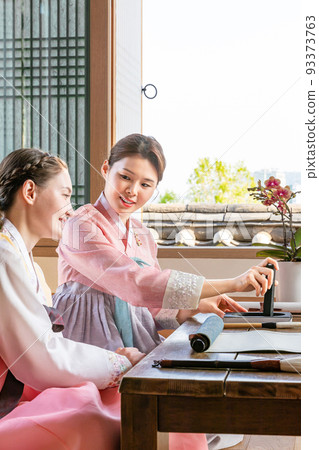 Korean and Caucasian girls Experiencing traditional calligraphy in Hanok, Korean traditional house 93373763