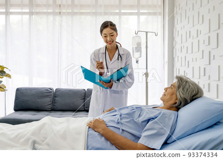 Young asian doctor in white gown with stethoscope and document folder, examine the symptom of the elderly patient in the recovery room. Healthcare and medicine concept Young asian doctor in white gown with stethoscope and document folder, examine the symptom of the elderly patient in the recovery room. Healthcare and medicine concept 93374334