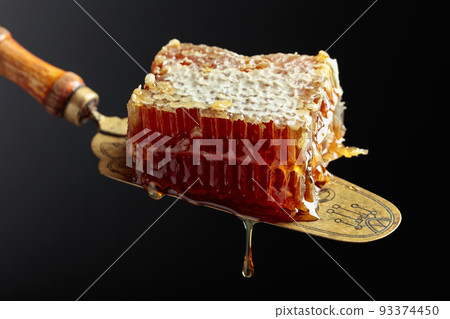 Honeycombs on an antique brass spatula. 93374450