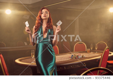 Young beautiful woman is posing against a poker table in luxury casino. Young beautiful woman is posing against a poker table in luxury casino. 93375446