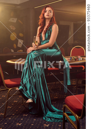 Young beautiful woman is posing against a poker table in luxury casino. Young beautiful woman is posing against a poker table in luxury casino. 93375460