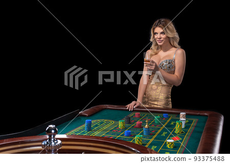 Young blonde woman wearing beautiful sexy shiny dress is playing roulette in the casino 93375488