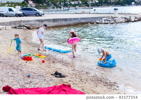 Sibling boy building a sandcastle at the beach in summer Sibling boy building a sandcastle at the beach in summer 93377354