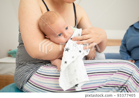 Mother holding and rocking baby sitting on fitball 93377405